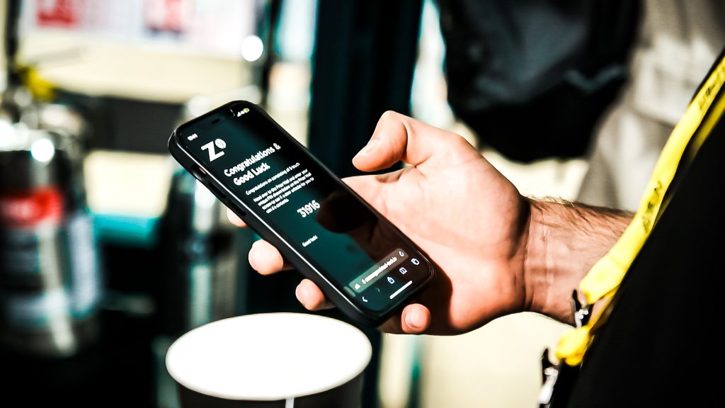 Close-up of a guest receiving their prize code on their phone after answering questions at the Noonah Prize Vault during the AI Summit.