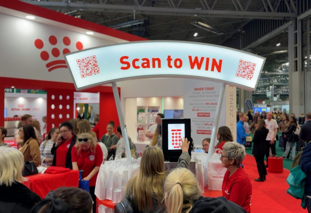 Noonah Prize Vault at the Royal Canin stand at Crufts, with a crowd gathered and a “Scan to Win” sign above the Vault
