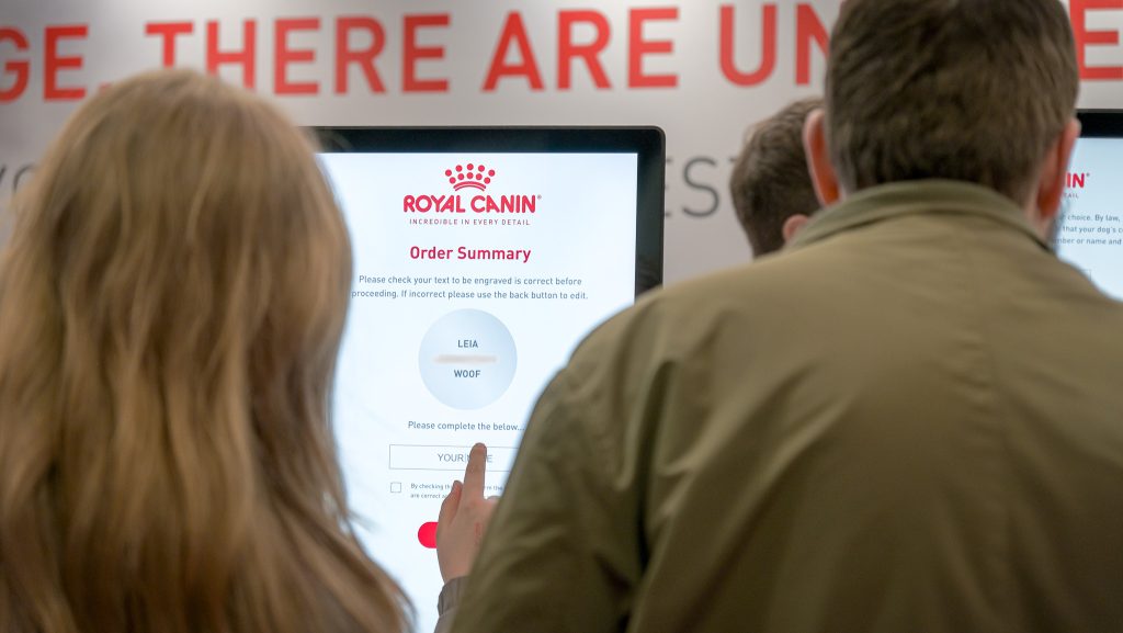 Guest adding custom engraving to a dog tag at Crufts, showcasing personalised pet engraving at live events.