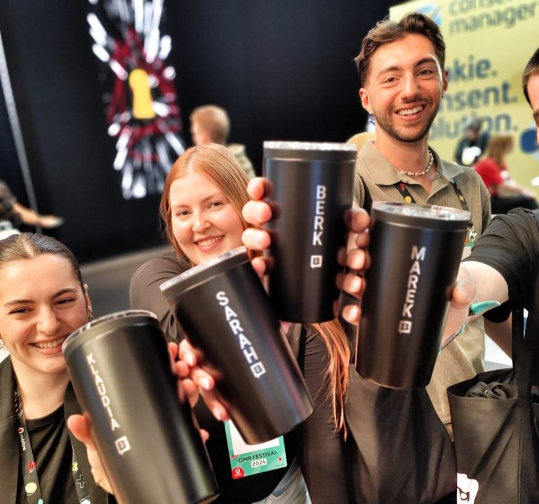 Guests smiling and holding their personalised engraved travel mugs at a live event