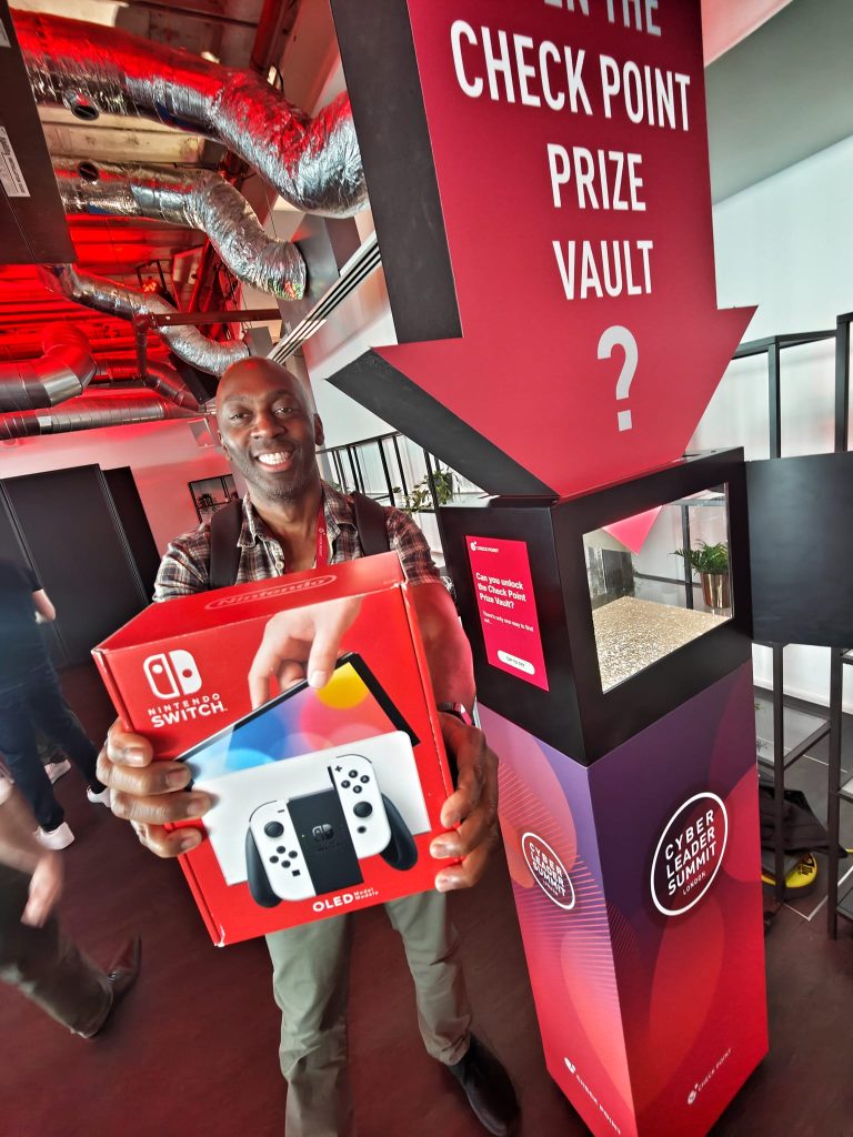 Guest standing next to our Prize Vault at the Cyber Leader Summit, celebrating winning a Nintendo Switch.