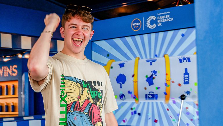 Guest celebrating a spin-to-win prize on Noonah’s one-arm bandit smart vending machine at the Nivea Sun Safety Tour during Tramlines music festival.