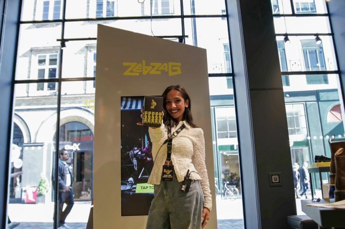 Girl holding up her free gift in front of Dr Martens Vending Machine in retail store