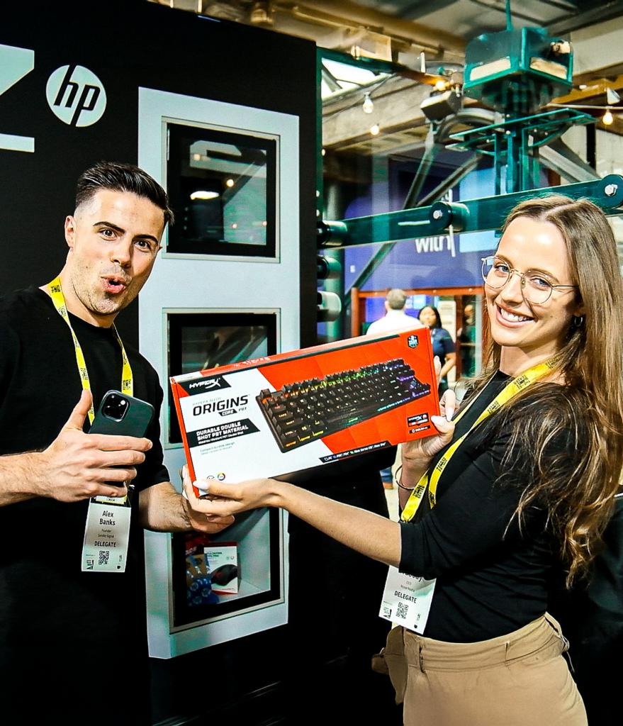 Two winners showing their prize from our Prize Vault on the HP stand during the AI Summit.